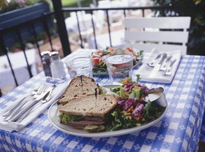 Un sandwich, salade, et le verre d'eau sur une table de café en plein air.