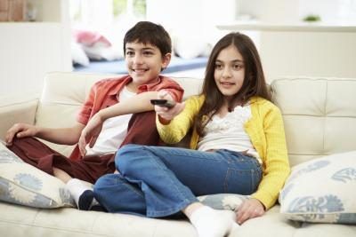 Deux enfants sont assis sur le canapé et regarder un film ensemble.