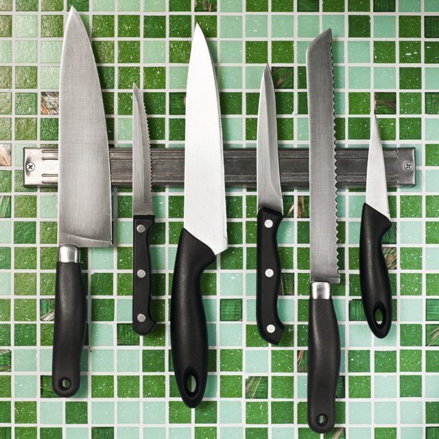 Couteaux en acier inoxydable pendent sur un aimant dans une cuisine.