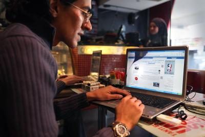 L'homme utilisant un ordinateur portable dans le café égyptienne pour voir Facebook